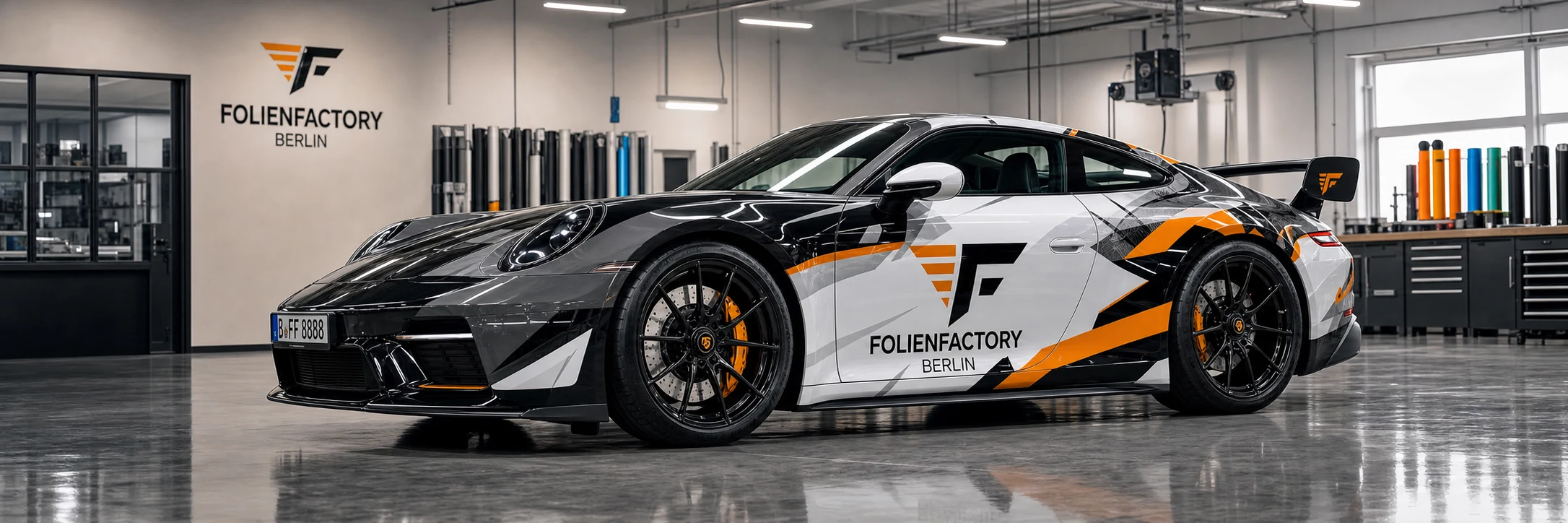 FolienFactory Sportwagen mit schwarz-weiß-oranger Folierung in einer modernen Werkstatt
